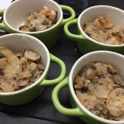 Cassolettes de Saint-Jacques -Beurrer des petites cocottes allant au four et ajouter dans chacune d'elles le mélange oignons et champignons, les noix de Saint-Jacques, quelques crevettes et du persil.