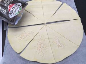 Recette minis croissants feuilletés à la coppa et au parmesan - Séparer les triangles de pâte et les parsemer individuellement de parmesan et poser une demi-tranche de coppa.