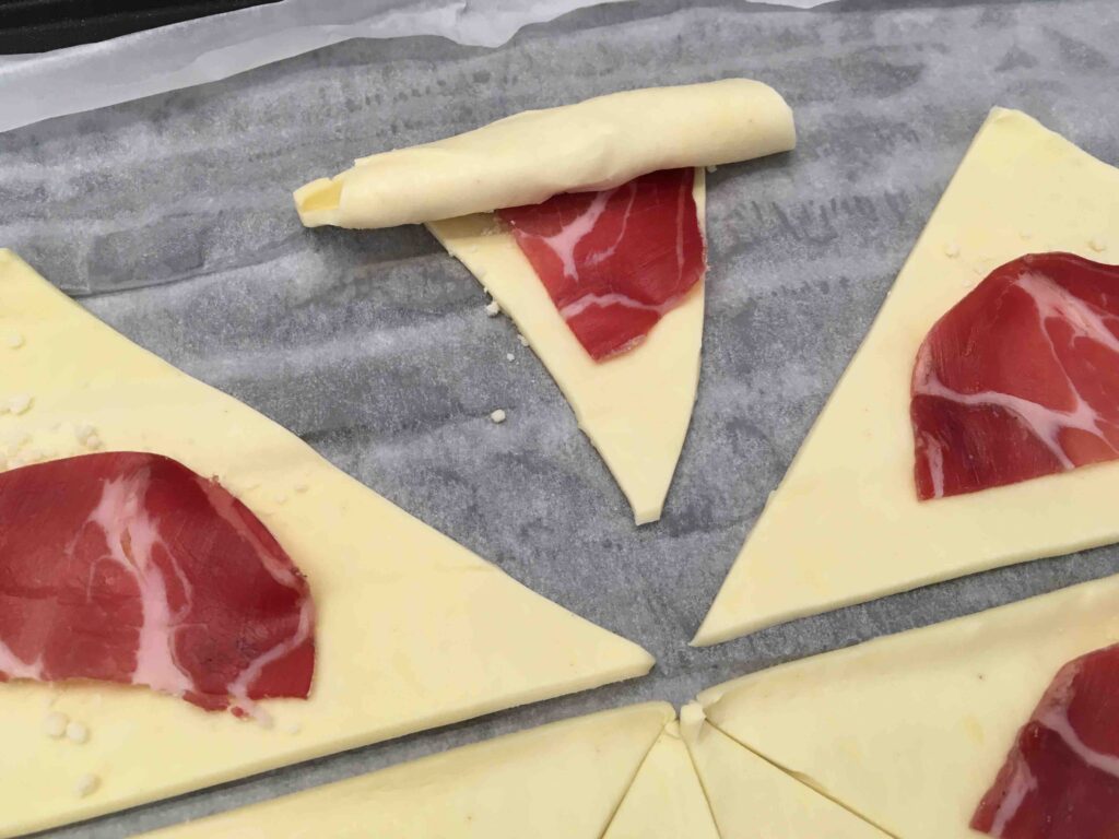 Recette minis croissants feuilletés à la coppa et au parmesan - Rouler les triangles de l'extérieur vers l'intérieur pour former des petits croissants.