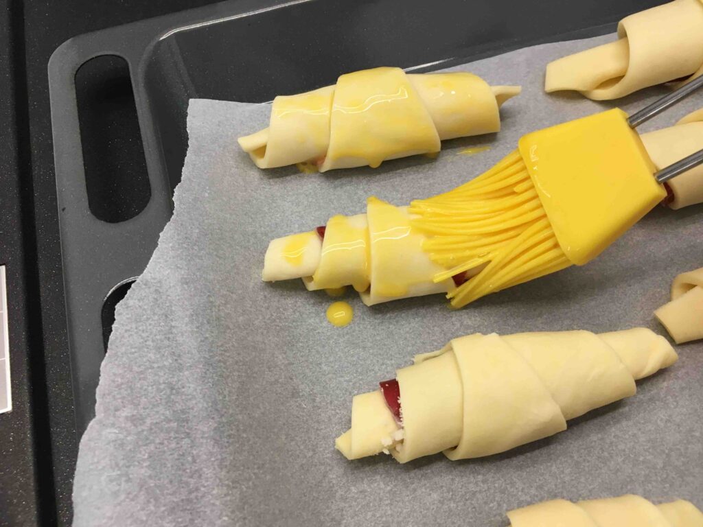 Recette minis croissants feuilletés à la coppa et au parmesan - Mélanger le jaune d'oeuf avec un peu d'eau et recouvrir les croissants de cette mixture à l'aide d'un pinceau.