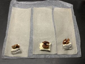 Recette croustillant noix camembert -Couper des bandes de bricks d'environ 10 cm. Déposer un morceau de camembert en bas de chacune d'elle puis 2 cerneaux de noix par dessus.