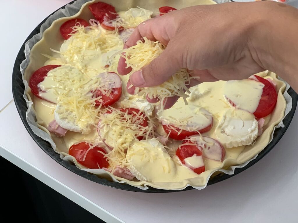 Recette quiche à la tomate, au jambon et au chèvre -Verser cette préparation sur la quiche et parsemer de gruyère râpé.