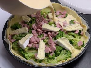 Recette quiche au camembert brocolis et jambon -Dans un saladier, fouetter les oeufs avec la crème fraîche. Saler et poivrer. Verser sur la pâte.