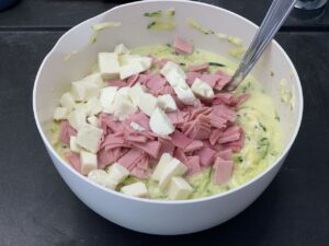 Recette quiche aux courgettes fromage et jambon -Verser les courgettes, le jambon coupé en petits carrés et la mozzarella coupée en morceaux. Bien mélanger pour bien incorporer les ingrédients à la pâte.