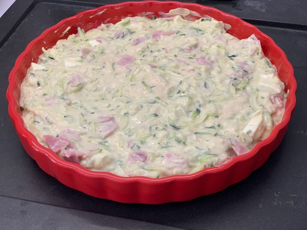 Recette quiche aux courgettes fromage et jambon -Beurrer un moule à tarte et y verser la préparation.