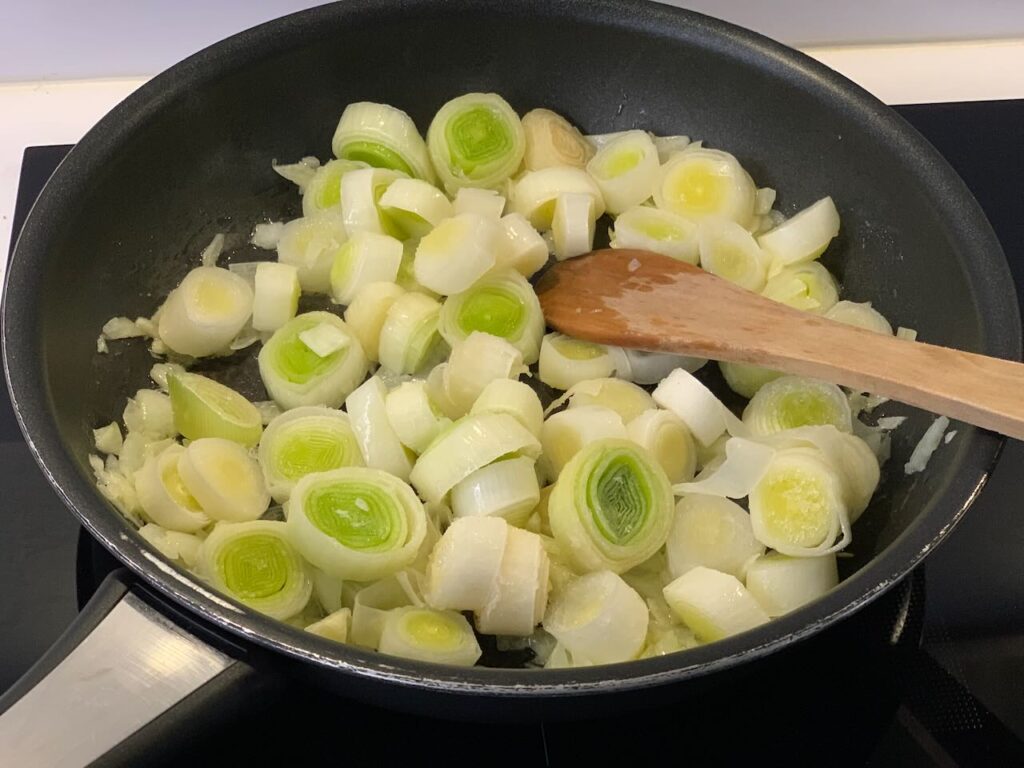 Recette velouté de poireaux et pommes de terre au pesto -Dans une casserole, faites revenir l'oignon et les poireaux dans le beurre avec un peu de sel pendant une dizaine de minutes à feu moyen.