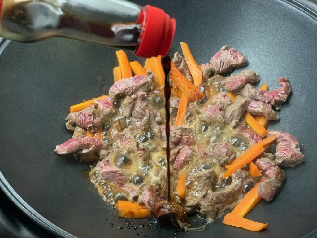 Nouilles au boeuf sautées sauce soja sucrée -Ajouter la sauce soja et porter à ébullition 5 minutes. Stopper la cuisson pour ne pas durcir la viande.