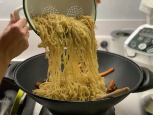 Nouilles au boeuf sautées sauce soja sucrée - Ajouter les nouilles dans la viande et parsemer de graines de sésame.