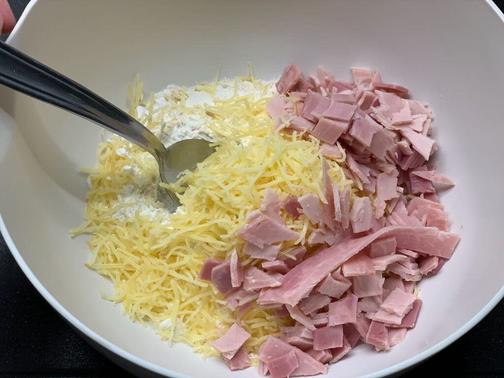Recette cookies salés au jambon et comté -Dans un saladier, mélanger la farine, le fromage, la levure, le sel et les dés de jambon.