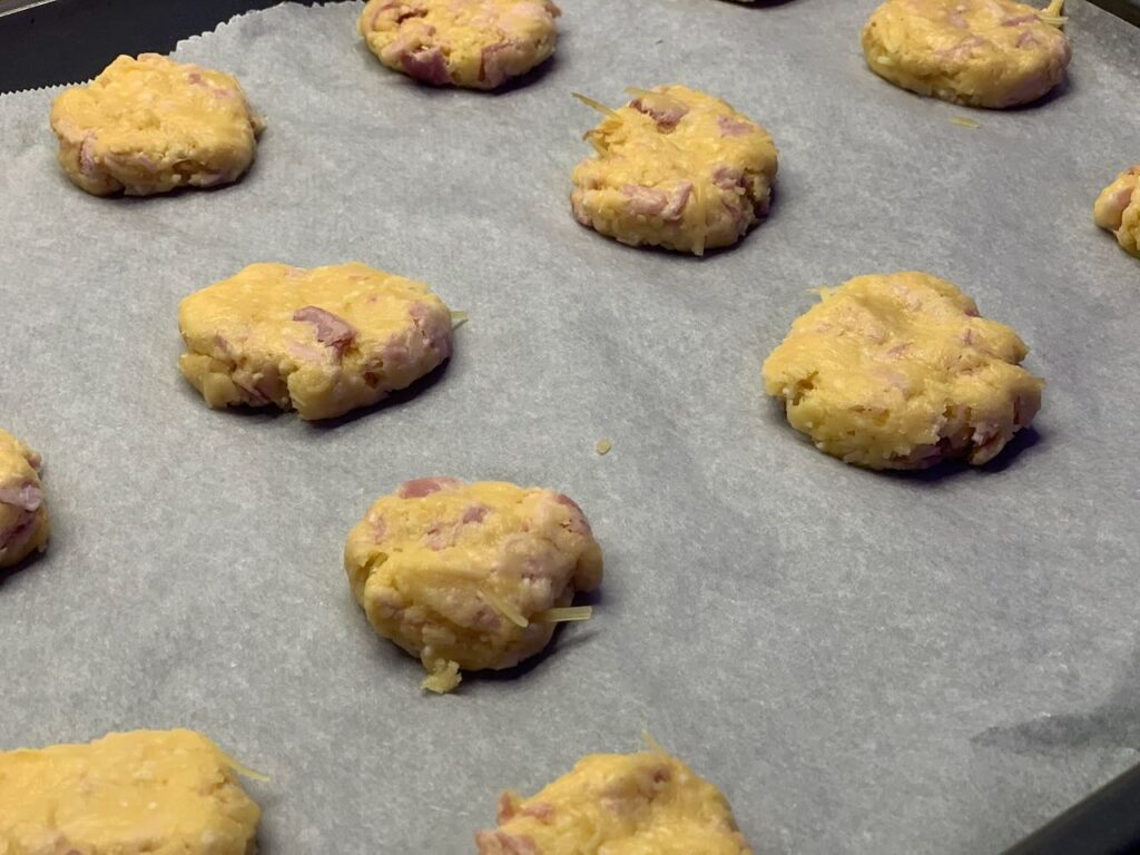 Recette cookies salés au jambon et au comté -Recouvrer une plaque de cuisson de papier sulfurisé et disposer dessus de petites boules de pâte de la taille d'une noix.
Aplatir avec la main.