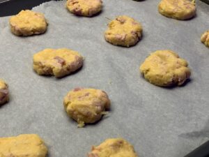 Recette cookies salés au jambon et au comté -Recouvrer une plaque de cuisson de papier sulfurisé et disposer dessus de petites boules de pâte de la taille d'une noix. Aplatir avec la main.