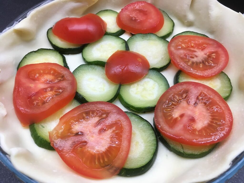 Recette quiche aux tomates et aux courgettes - Répartir les tomates et courgettes en les alternant et en les faisant se chevaucher.